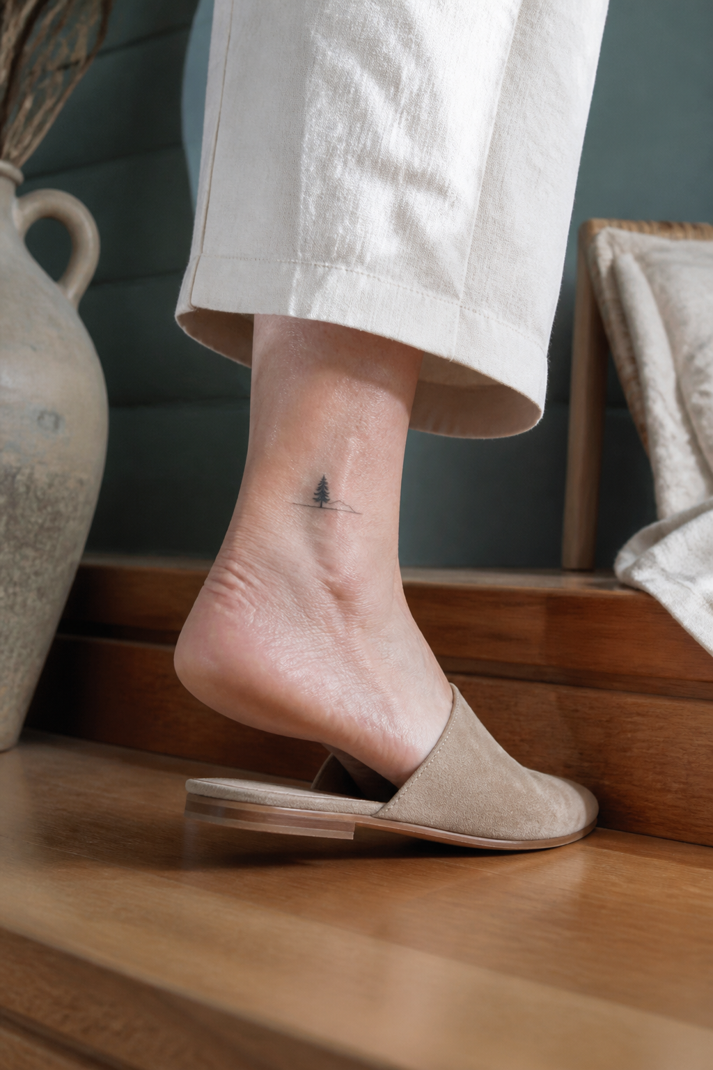 Tiny pine tree and horizon outer-ankle tattoo