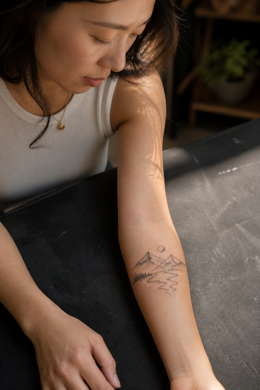 Fine-line mountain river outer-forearm tattoo