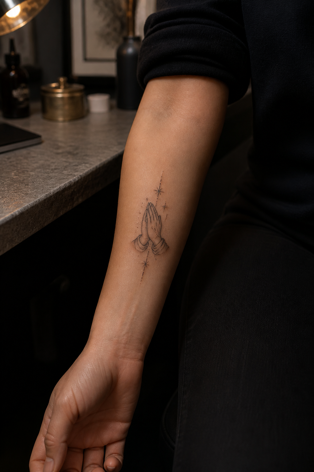 Fine line praying hands tattoo on the inner forearm