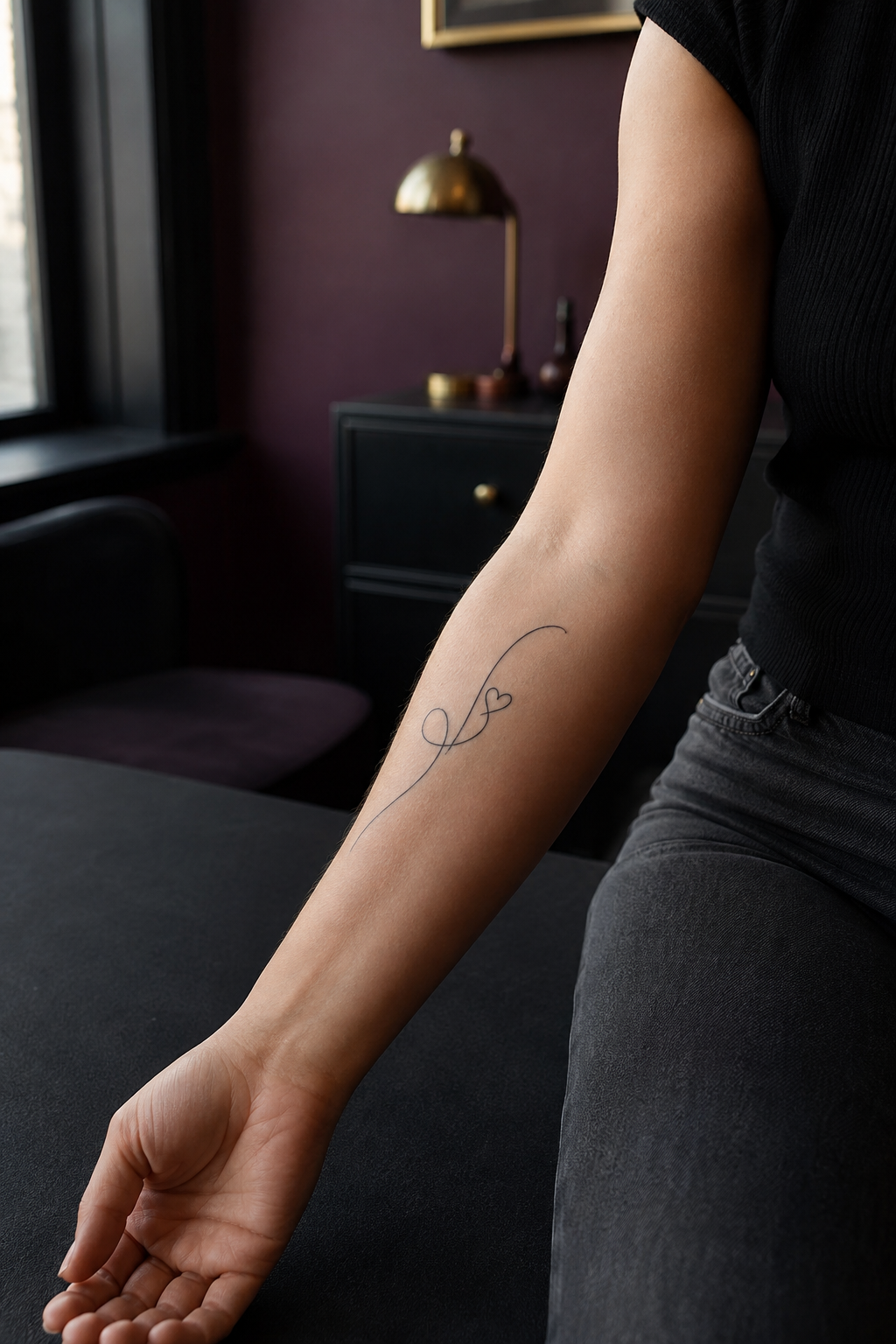 Fine script-like line ending in a tiny heart on a forearm
