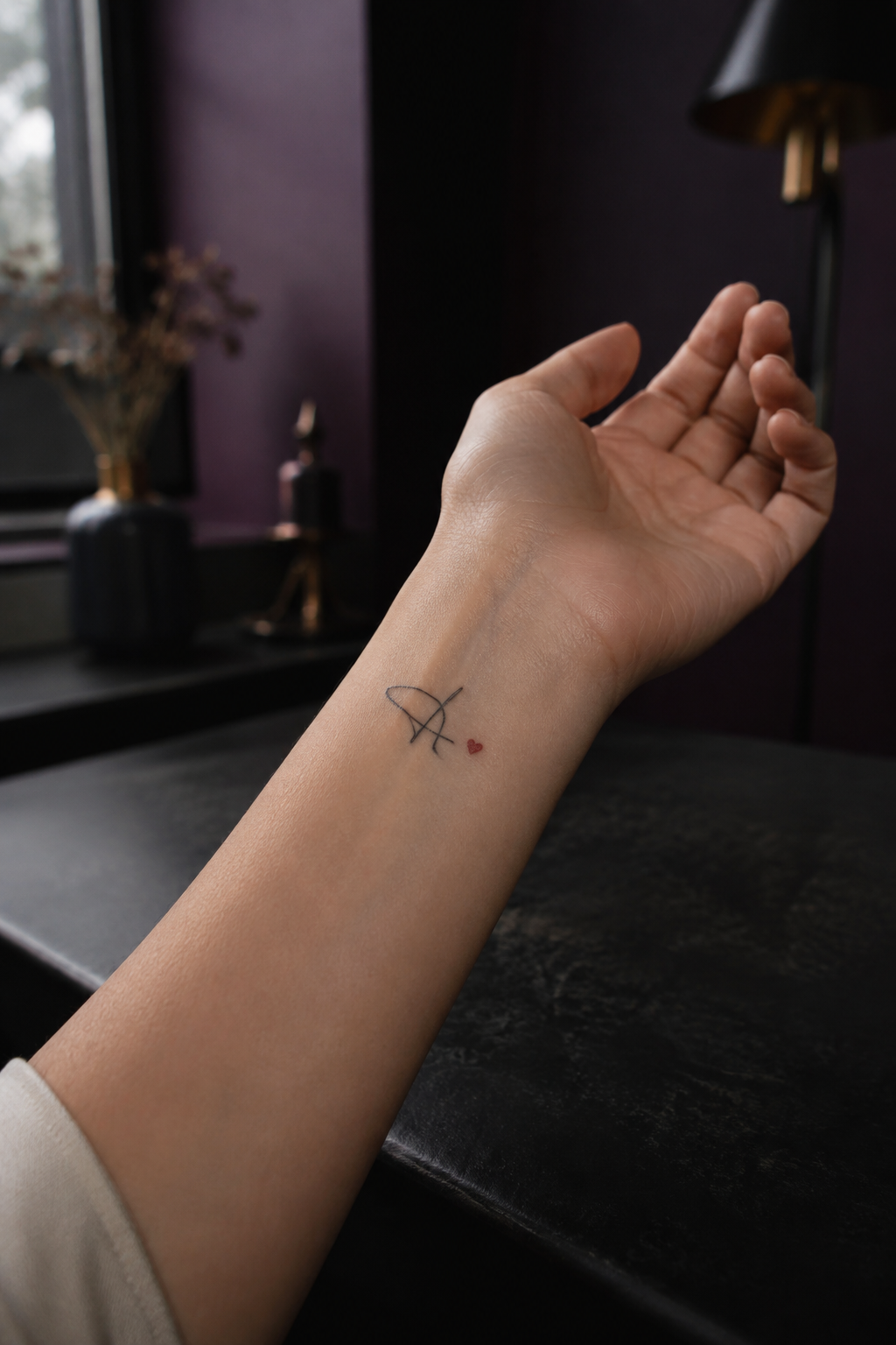 Tiny abstract initial and red heart wrist tattoo